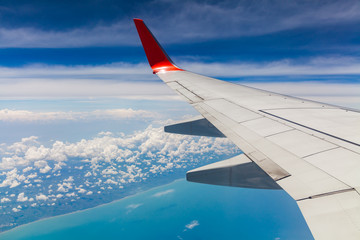 Aerial view of cloud blue sky and plane wing view through the airplane window.