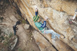 © Manu Prats - High angle view of climber reaching across for handhold on rock face in granite wall