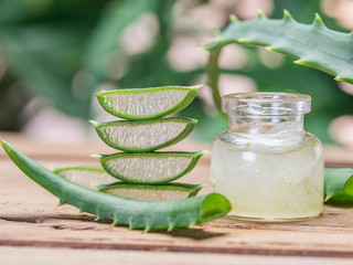 Wall Mural - Fresh aloe leaves and aloe gel in the cosmetic jar on wooden table.