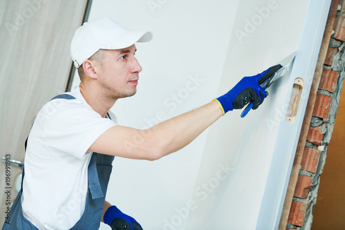 Fotomural refurbishment. Worker spackling a wall with putty