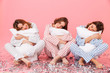 © Drobot Dean - Photo of sleepy women 20s wearing leisure clothings holding pillows and taking pleasure during slumber party, isolated over pink background