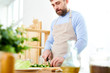 © Seventyfour - Mid section portrait of handsome mature man cooking salad and cutting vegetables in spacious kitchen at home, copy space