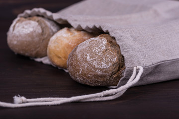 Homemade bread in a natural linen bag for storage on wooden background