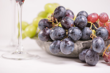 Fresh grape and red wine on the white table with two glasses, selective focus