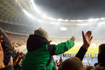 the child sits on his father's shoulders and supports his football club