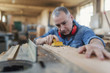 © Dragana Gordic - Man doing woodwork in carpentry. Carpenter work on wood plank in workshop
