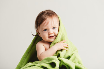 Wall Mural - Cute little baby leaning out of cozy green blanket.