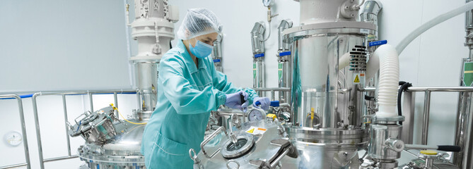 pharmaceutical factory woman worker in protective clothing operating production line in sterile envi