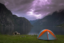 View Of A Camp Tent By A Lake Against Cloudy Sky