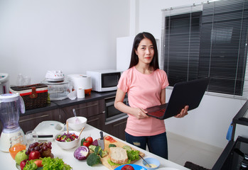 Sticker - woman cooking and looking with laptop in kitchen room