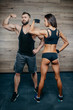 © Roman Tyukin - Muscular man with tattoos and beard and stunning brunette girl posing in a gym. Sportive shredded couple.
