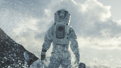 Wall Mural - shot of the astronaut walking through blizzard on frozen alien planet towards his base/ research sta