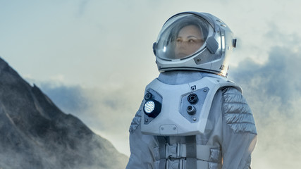 Wall Mural - shot of female astronaut in the space suit looking around frozen alien planet. advanced technologies