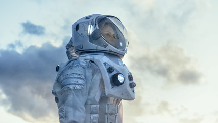 Wall Mural - shot of female astronaut in the space suit looking around frozen alien planet. advanced technologies