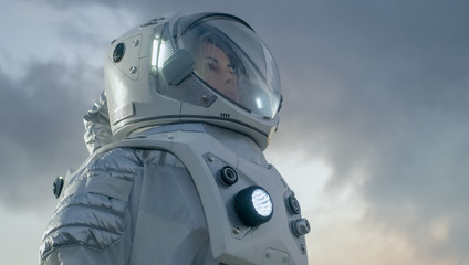 Wall Mural - shot of female astronaut in the space suit looking around frozen alien planet. advanced technologies