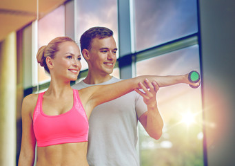 Canvas Print - smiling young woman with personal trainer in gym