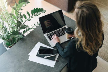 Rear view.Young businesswoman is standing near table, working on laptop.Online marketing,education,e-learning,e-commerce