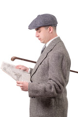 Wall Mural - young man in vintage clothes with hat, reading a newspaper, 1940 style