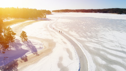 Wall Mural - Aerial view of frozen sea. People are skating on the ice.