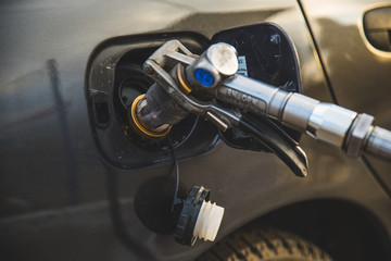 car fuel up with gas. close up refueling gun in the neck of the tank