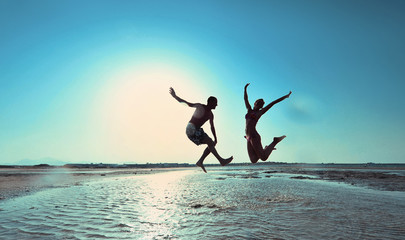 Happy young couple having beach fun on vacation honeymoon travel holidays. Caucasian woman and man playing playful enjoying love on date or honeymoon. Multiracial couple