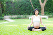 © NT_studio - Beautiful pregnant asian young woman relax in the park, girl with belly sitting with crossed leg on grass and yoga exercise for wellness, copy space.