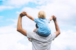© nataliaderiabina - Father and son with raised arms up against the sky.