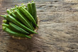 raw okra fruit in bamboo basket on old and crack wooden background with copy space. organic healthy food concept.