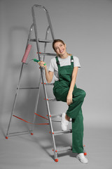 Wall Mural - Young female decorator with paint roller on color background