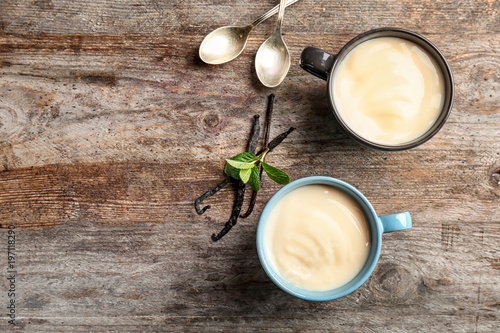 Fotomural Cups with vanilla pudding, sticks and fresh mint on wooden background