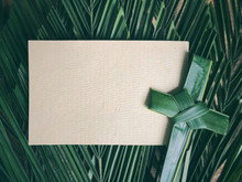Palm Sunday Concept. White Blank Paper And A Cross Made Of Palm Leaf. With Arranged Green Palm Leaves As Background.