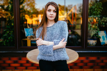 Young odd beautiful model girl with sensual pensive face posing for camera outdoor in front of shop showcase with abstract reflections in morning. Amazing teenager female with blue eyes mood portrait.