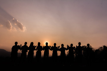 Wall Mural - Silhouette of cheering young generation Stand on the mountain at sunset.,Business concept idea