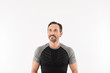 © Drobot Dean - Portrait of masculine man 30s wearing sportswear looking upward on copyspace with smile and satisfied look after doing sports, isolated over white background