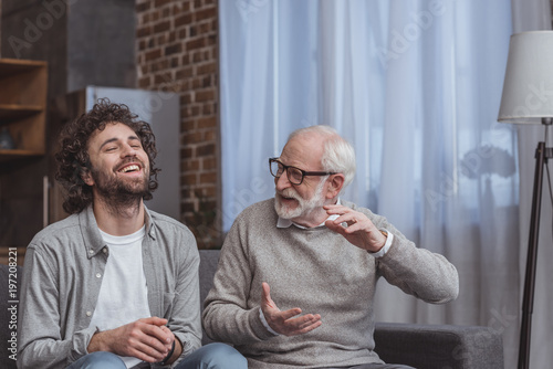 Zdjęcie: adult son and senior father talking and laughing at home adult son and senior father talking and laughing at home