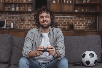 smiling handsome man playing video game at home