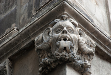 Gargoyle with protruding tongue. Architectural detail of old house in medieval town of  Arles. Provence, France.