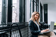 © bnenin - Portrait of a smiling blonde woman using laptop while sitting near the window.
