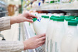 Woman takes bottle of milk from shelf in grocery