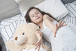 © Inga - Beautiful 7-8 year Old Girl Sleeping Girl in the Bedwith Teddy Bear with Copy Space. Flat Lay.