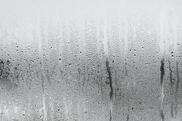 Blue background of natural water condensation, window glass with high air strong humidity, large drops drip. Collecting and streaming down