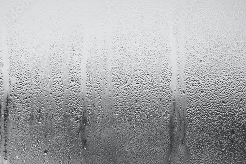 Blue background of natural water condensation, window glass with high air strong humidity, large drops drip. Collecting and streaming down
