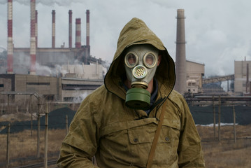 a man in a gas mask on a background of smoky pipes of a factory