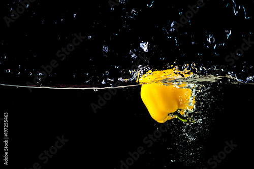 Zdjęcie XXL Świeża żółta papryka w wodzie bryzga na czarnym tle.