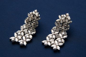 Pair of platinum earrings with diamond earrings, close-up. Luxury female gold jewelry