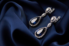 Pair Of Platinum Earring With Sapphire On Blue Satin Background. Luxury Female Jewelry, Close-up