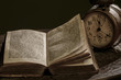 Geöffnetes, antikes Buch und eine alte Uhr