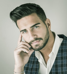 Wall Mural - Trendy young man in studio shot wearing elegant vest and white shirt, looking at camera