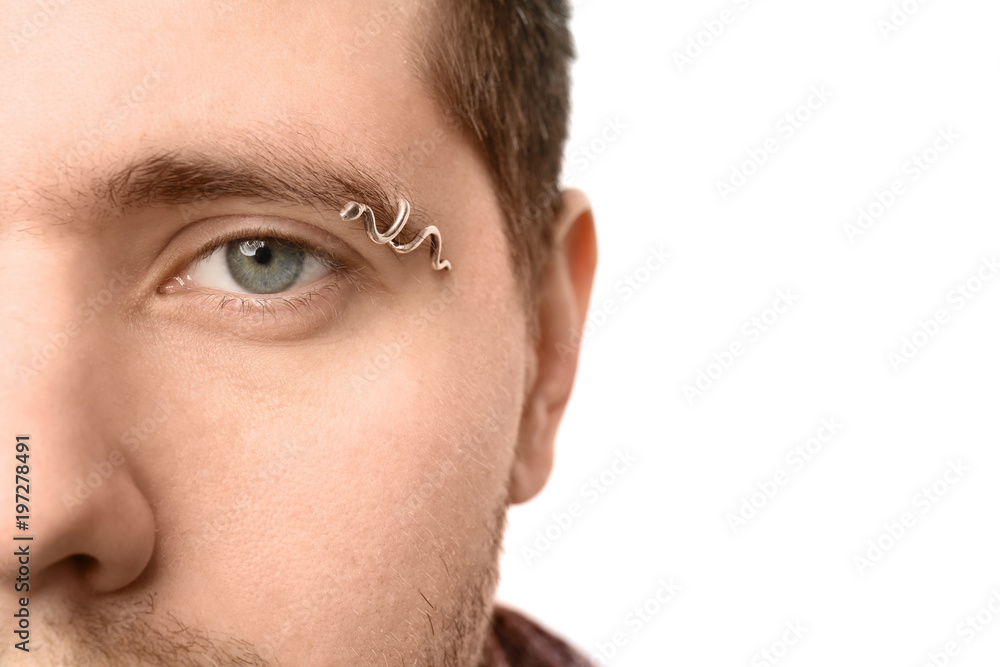 Young man with pierced eyebrow on light background, closeup