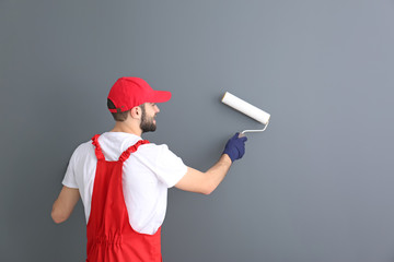 Poster - Male decorator painting wall with roller in room